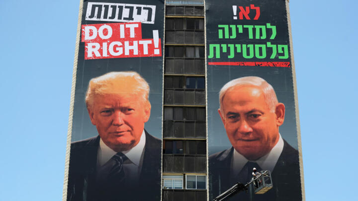 A labourer puts up banners depicting US President Donald Trump and Israeli Prime Minister Benjamin Netanyahu, bearing the words in Hebrew, "No to a Palestinian State" and "Sovereignty Do it right!" as part of a new anti-annexation campaign by the far-right Yesha Jewish settler council, in Jerusalem, on June 10, 2020.